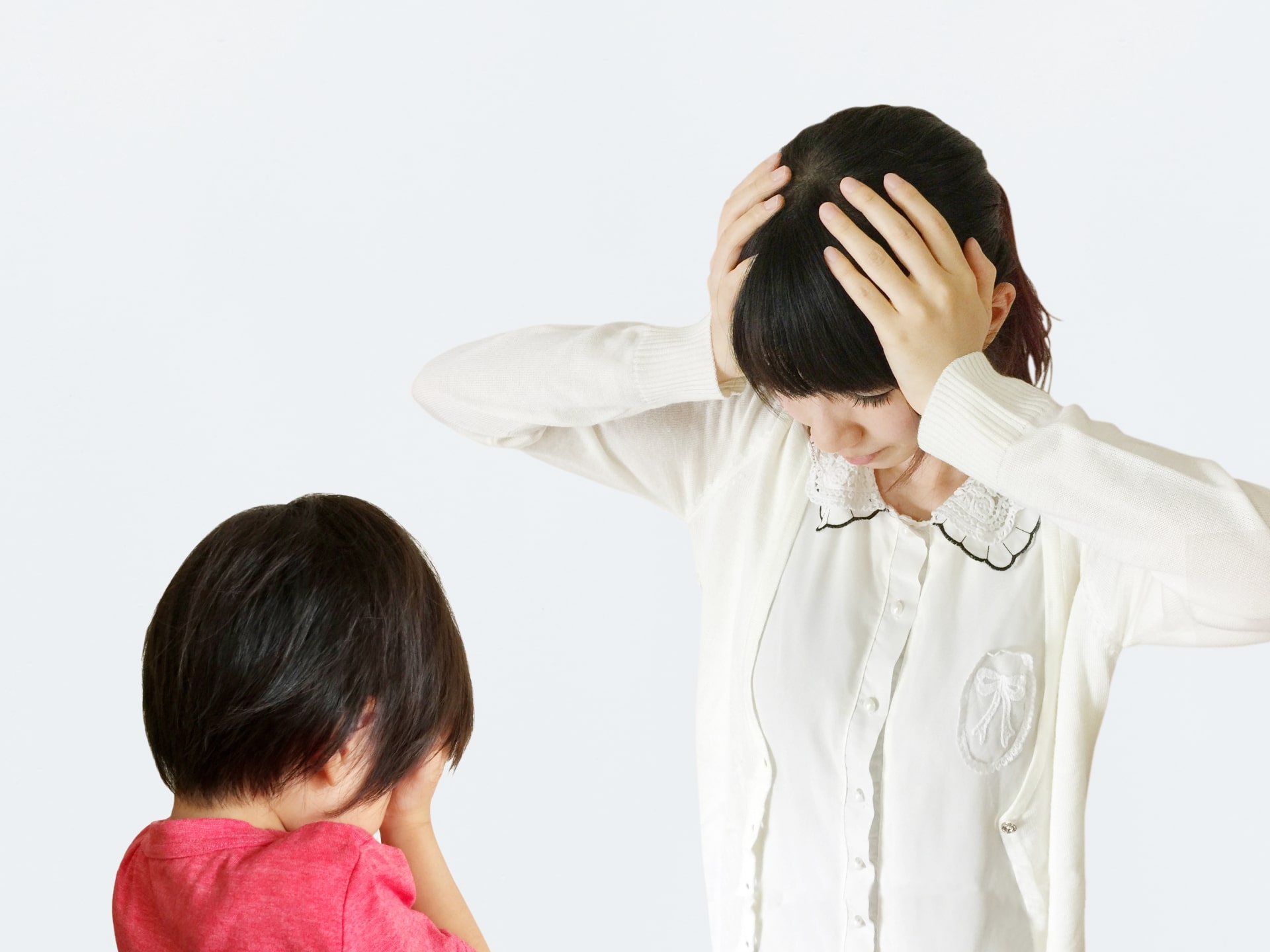 泣いている子どもに頭を抱える母親の写真